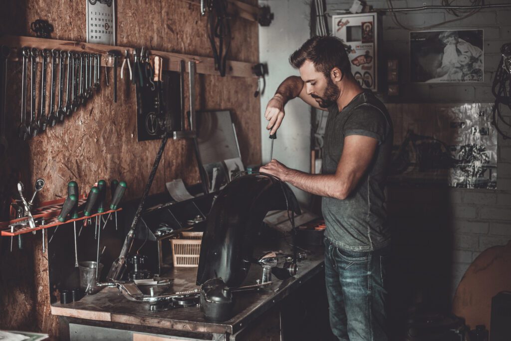 Man working on a car part on his workbench in a garage.