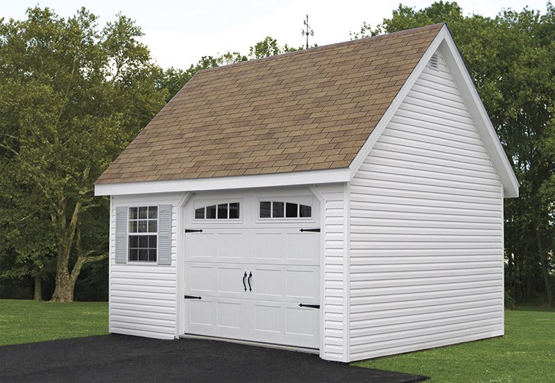 A while vinyl chalet one-car garage sits at the end of a driveway.