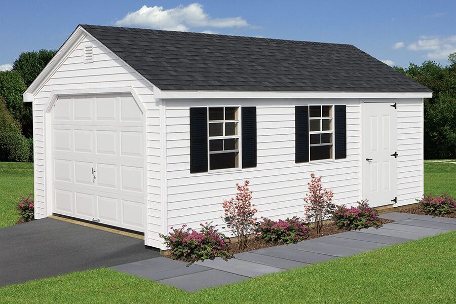 A white single-car garage sits at the end of a driveway surrounded by green grass and flowers.